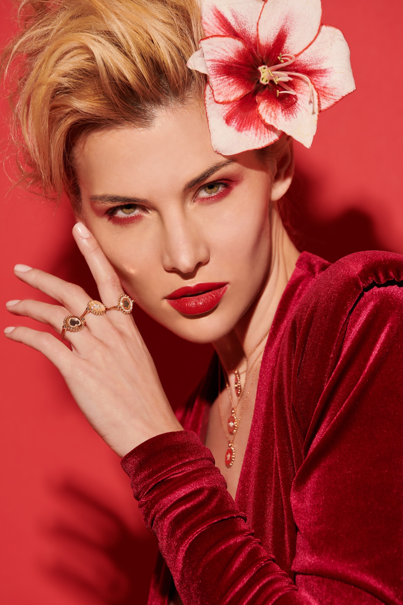 Ritratto con fiore rosso tra i capelli, anelli e collana d'oro