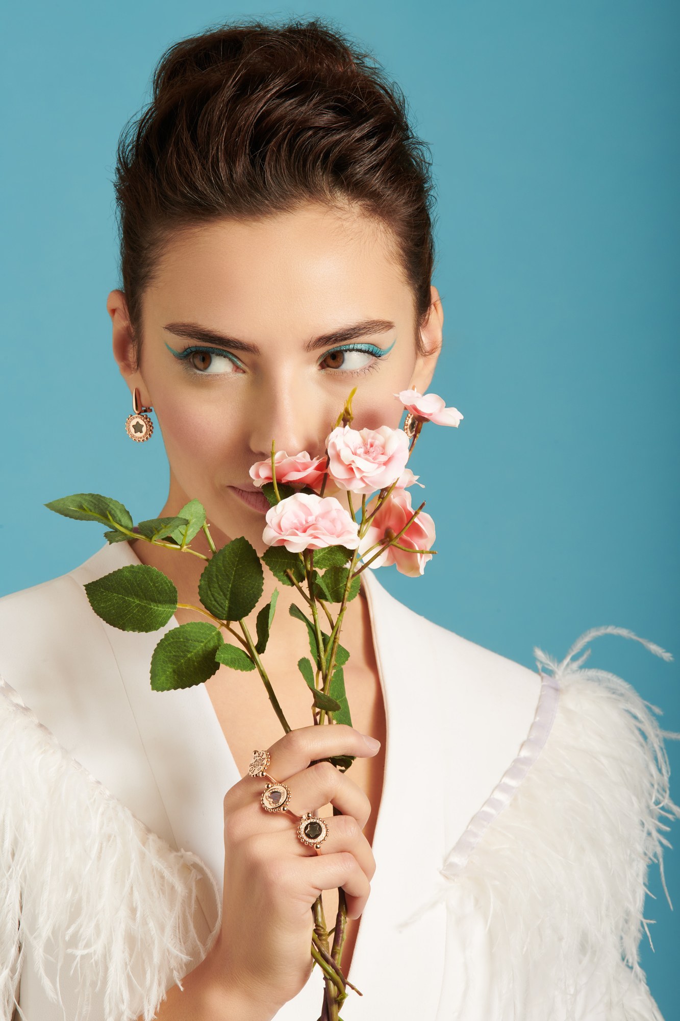 Modella con rose rosa e anelli su fondo azzurro