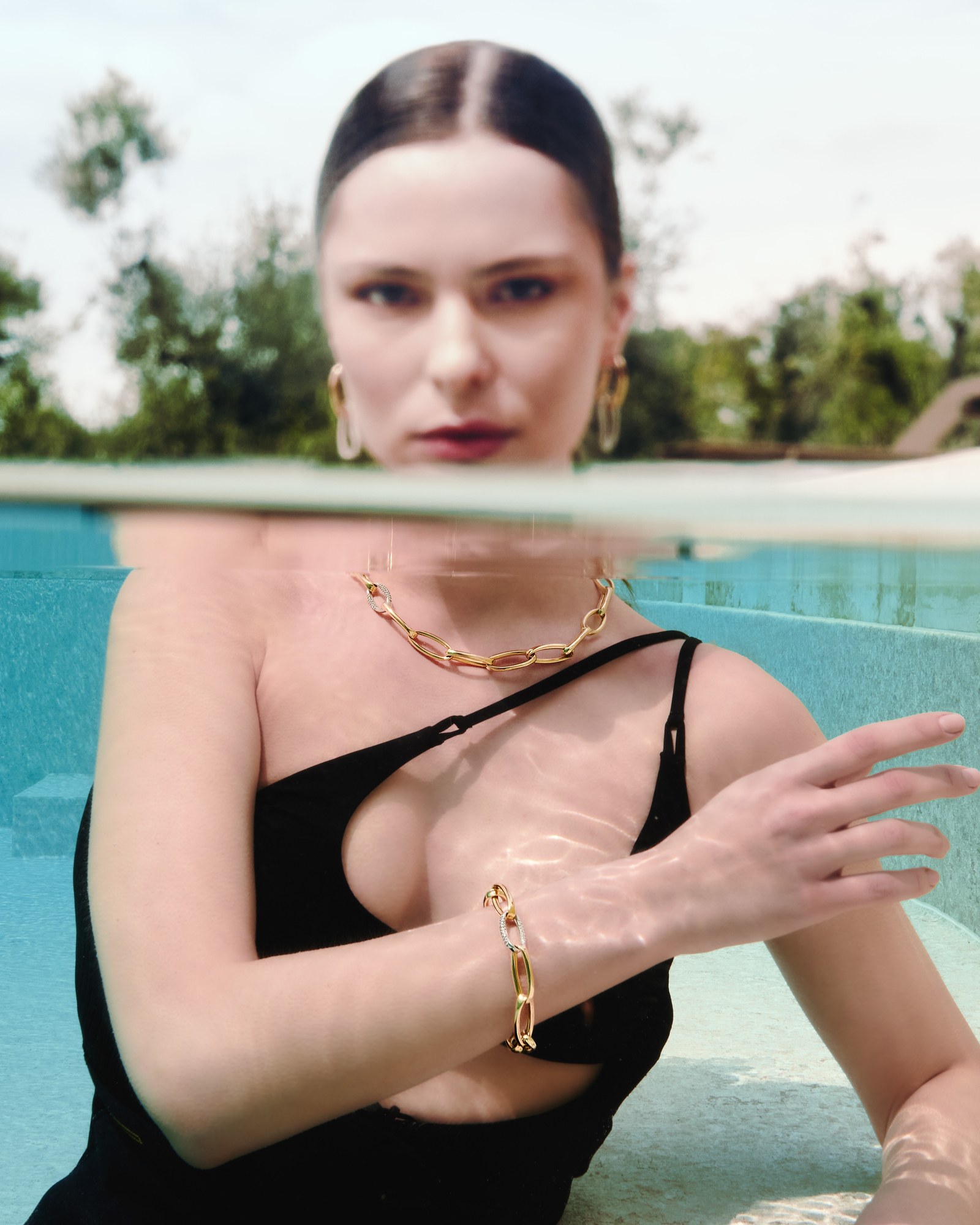 Modella in piscina con collana e bracciale d'oro