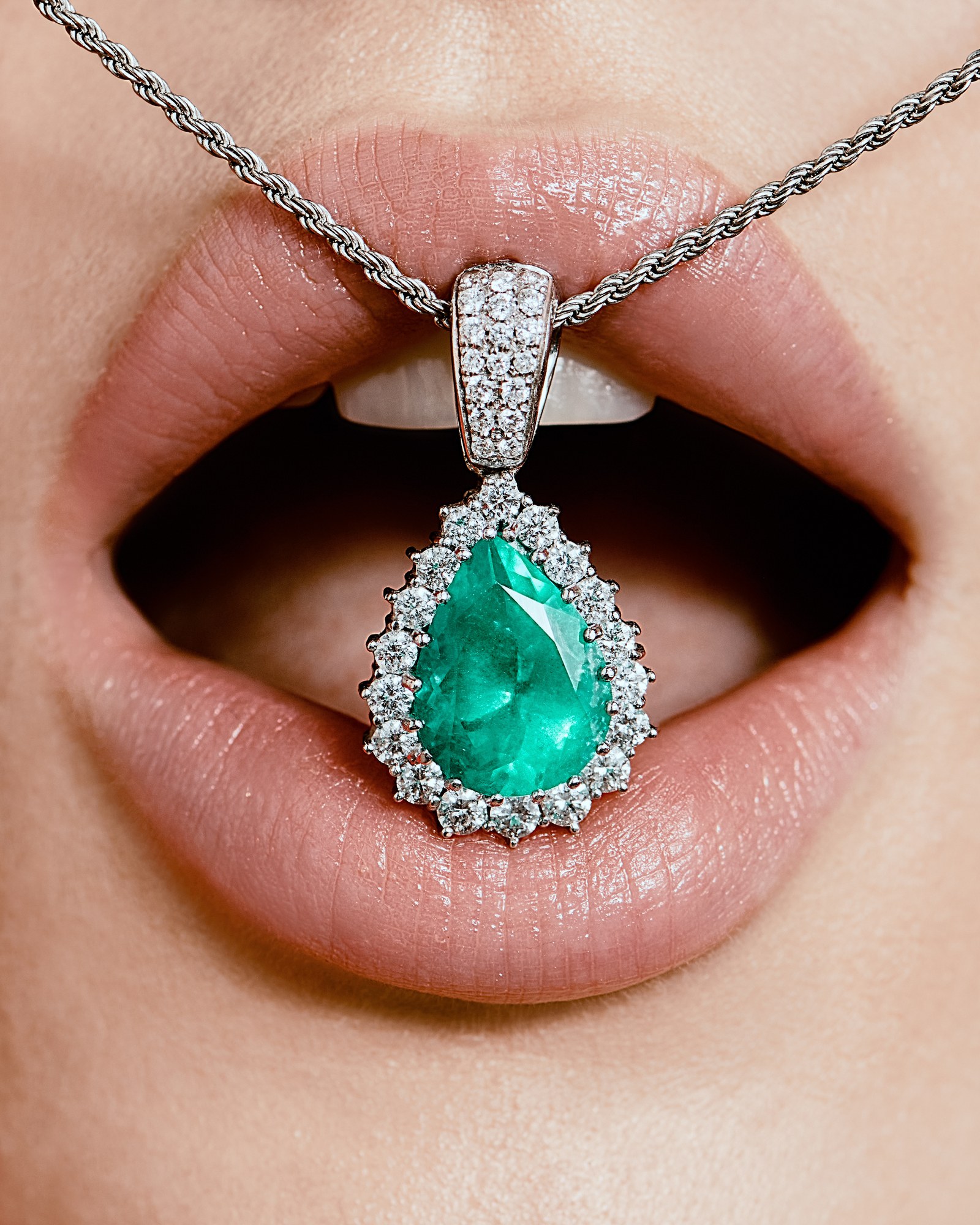 Labbra che stringono un pendente con smeraldo e diamanti