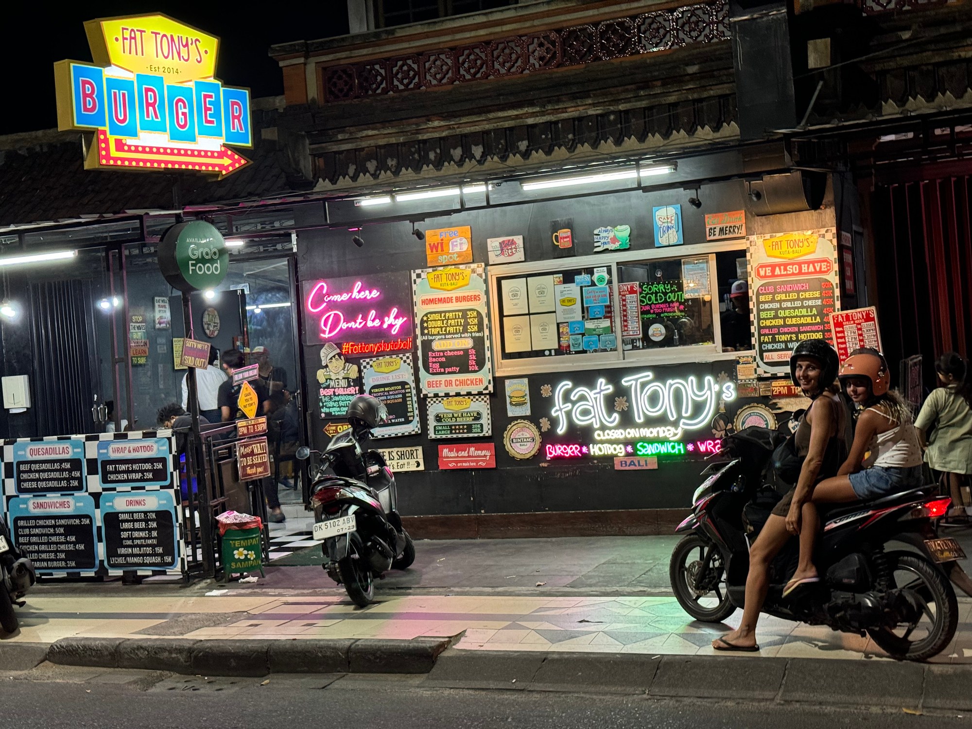 Locale con insegne al neon e scooter di notte