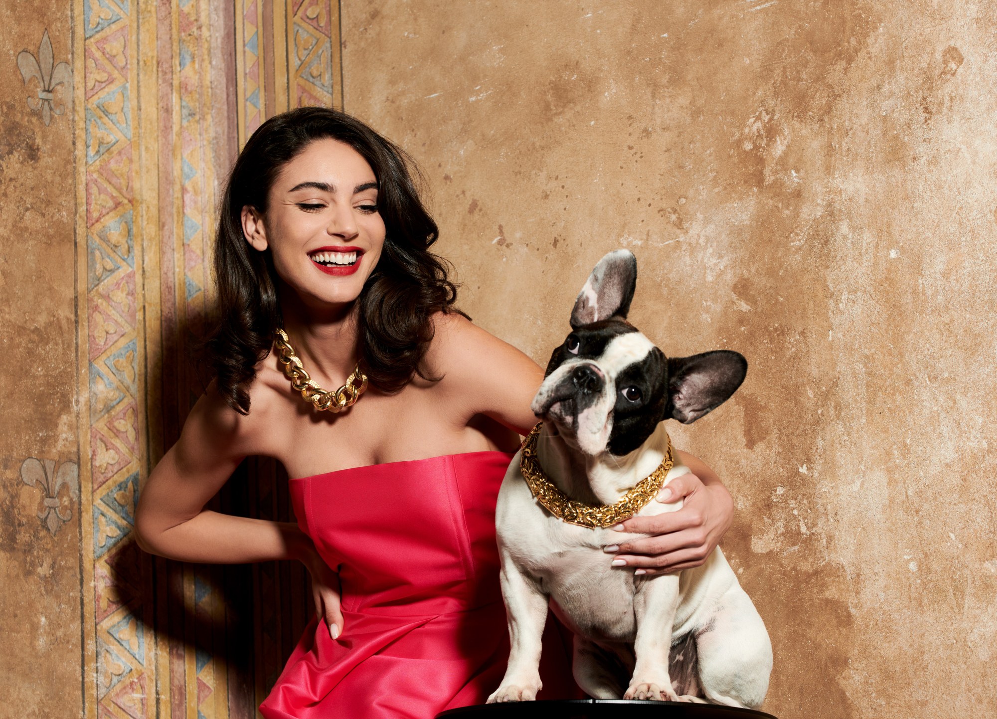 Modella sorridente con collana d'oro e bulldog francese