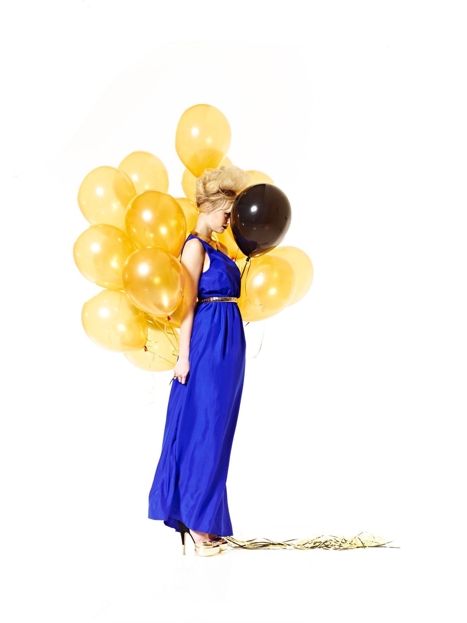 Modella in abito blu con palloncini dorati e neri