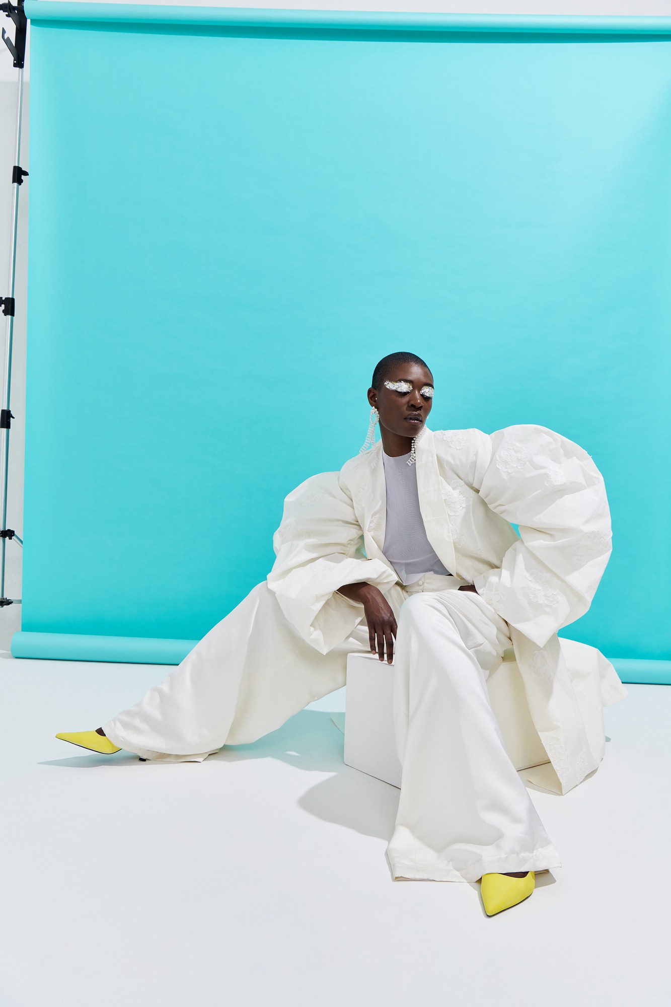 Modello in completo bianco oversize su fondale turchese