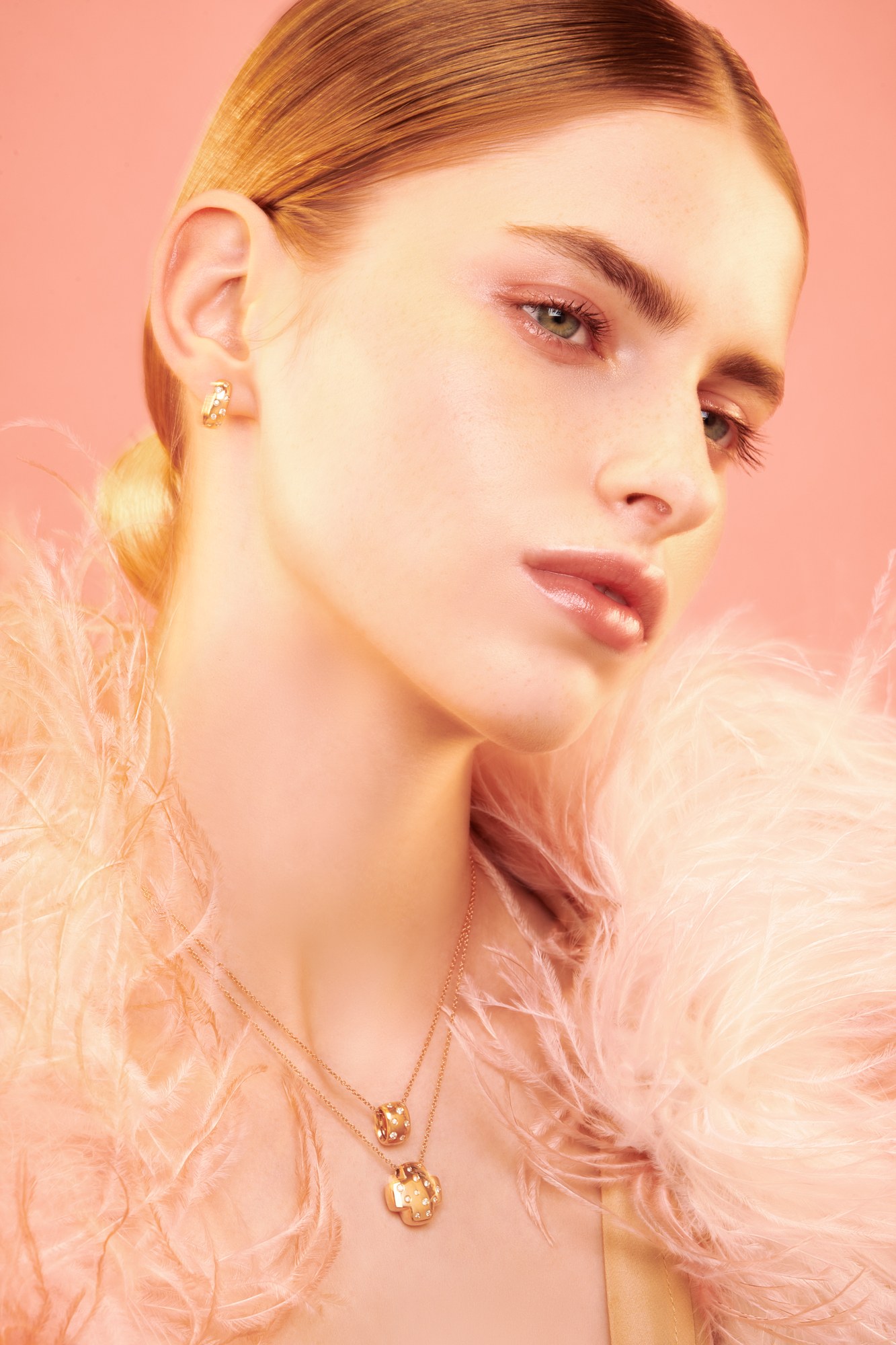 Ritratto beauty con piume rosa e gioielli dorati su fondo salmone