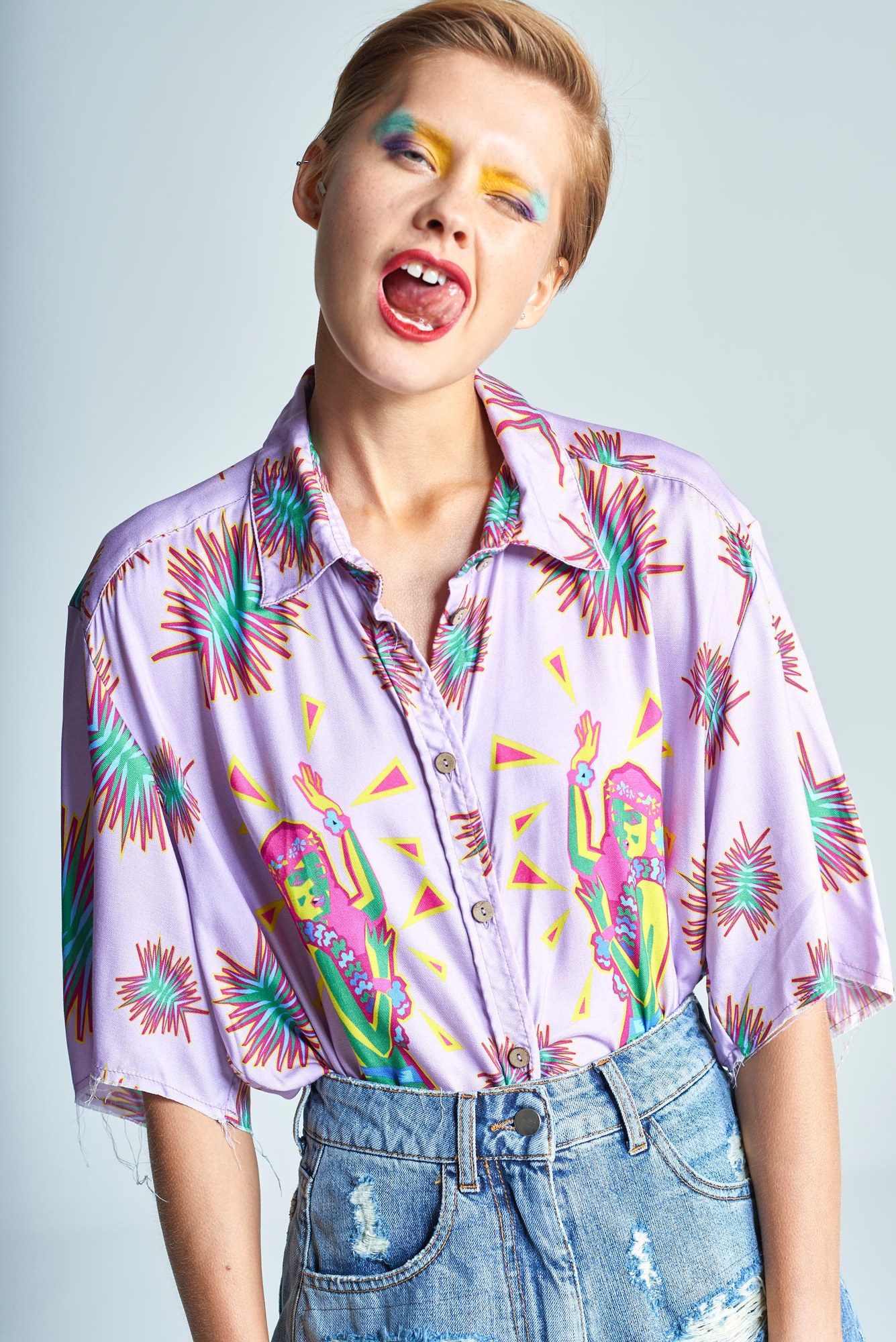 Ragazza con camicia stampata e trucco colorato in una smorfia ironica