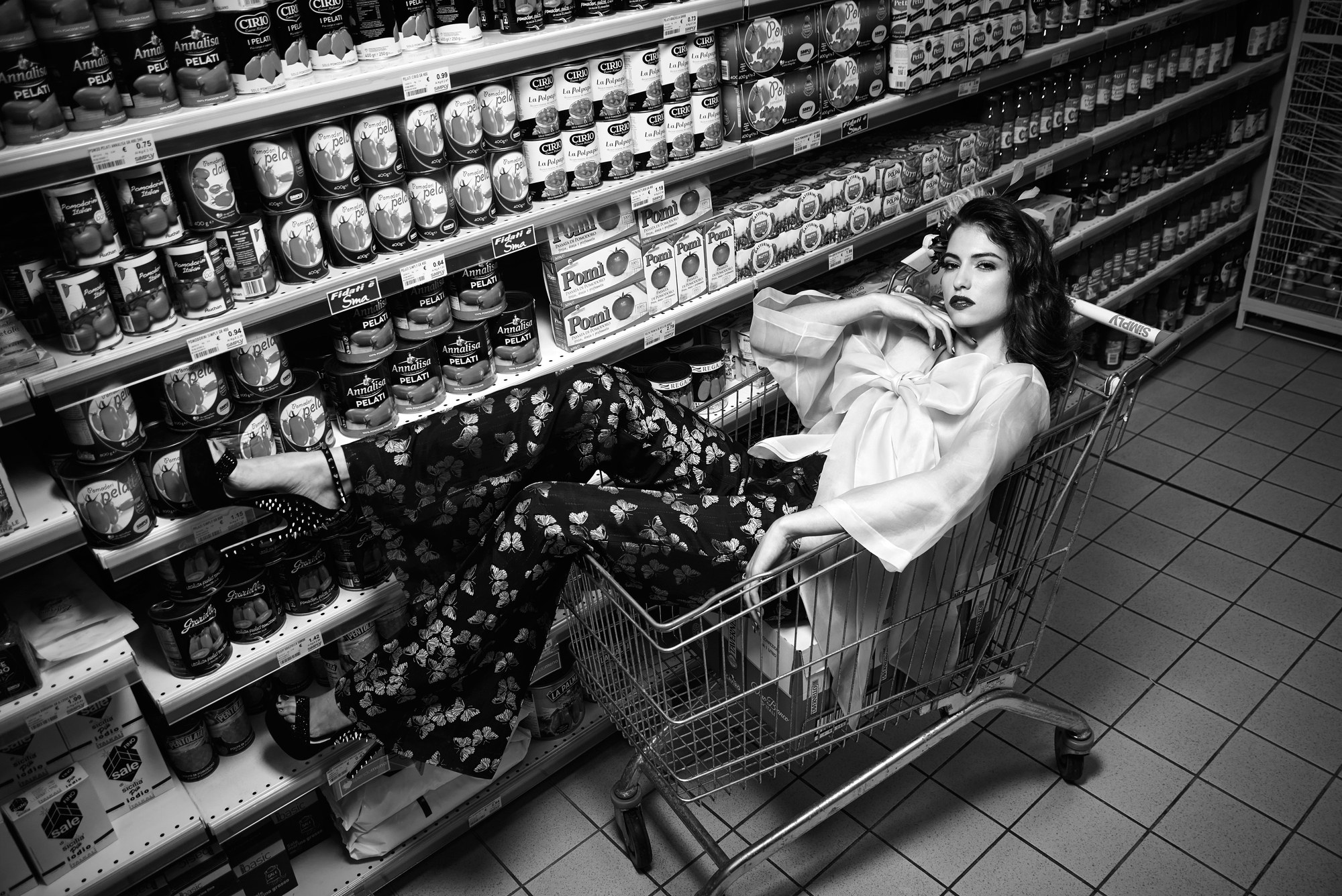 Modella seduta in un carrello del supermercato, editoriale in bianco e nero