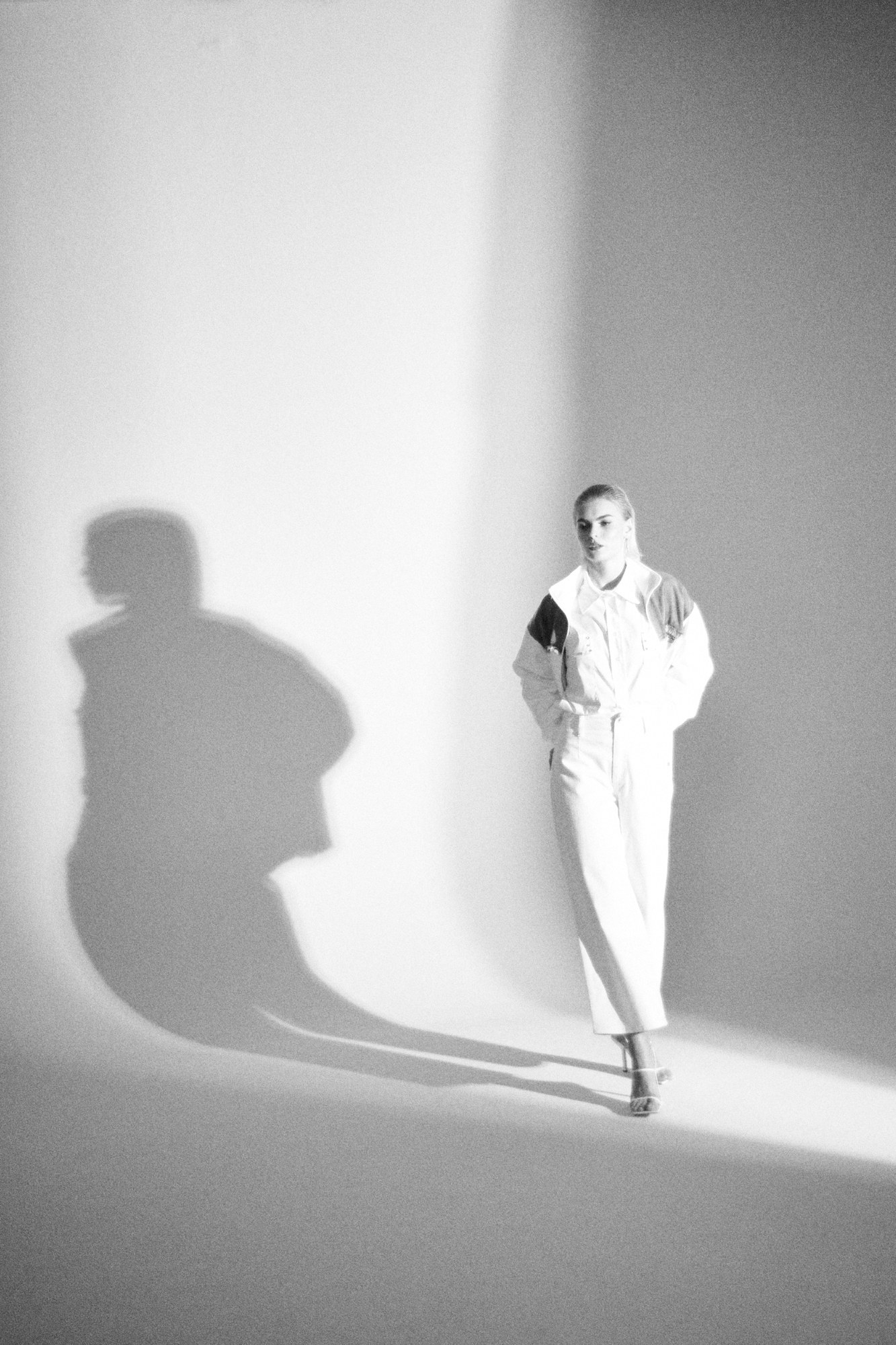 Figura in bianco con lunga ombra su parete bianca, bianco e nero