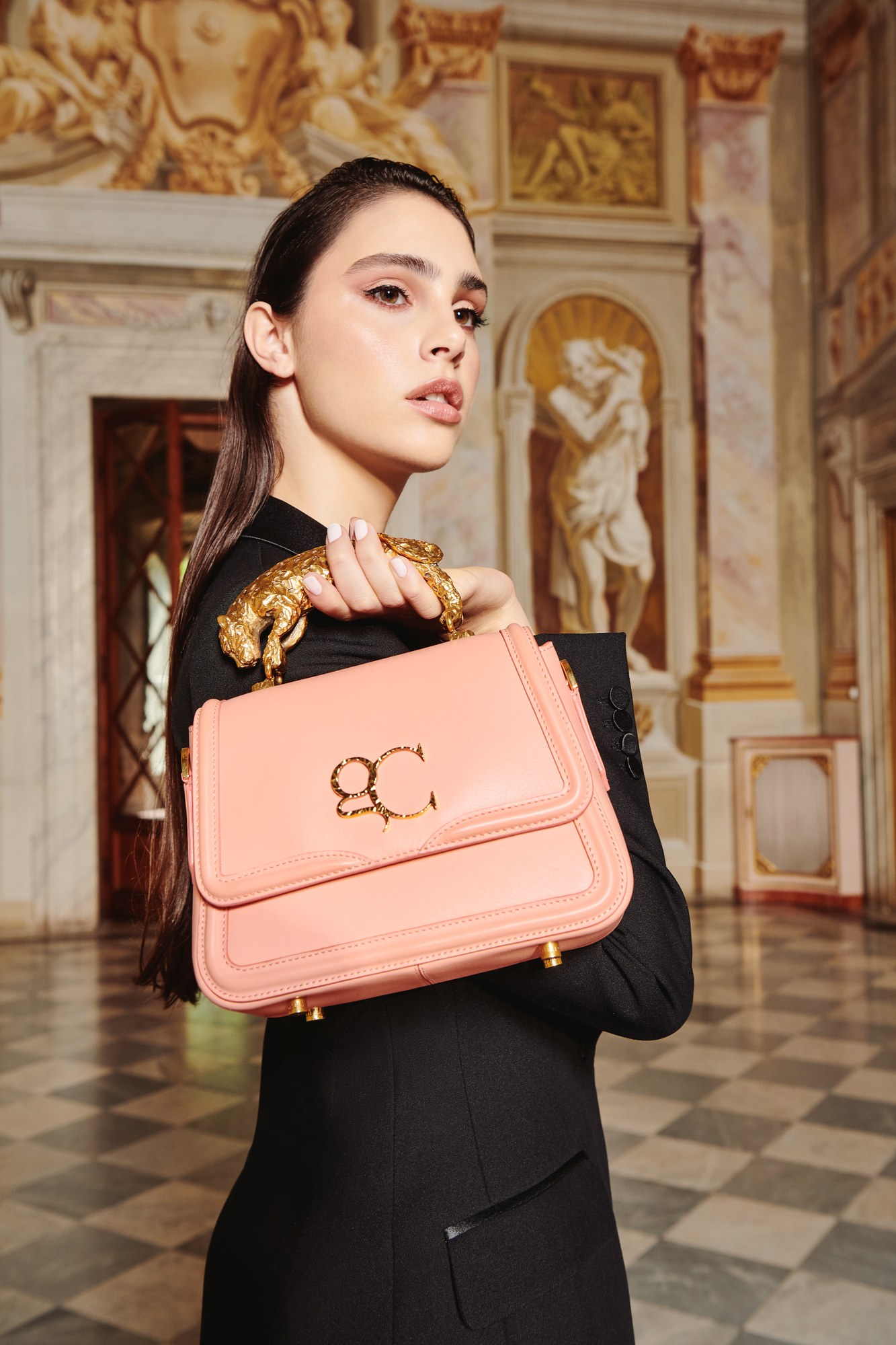 Modella con borsa rosa in un salone affrescato