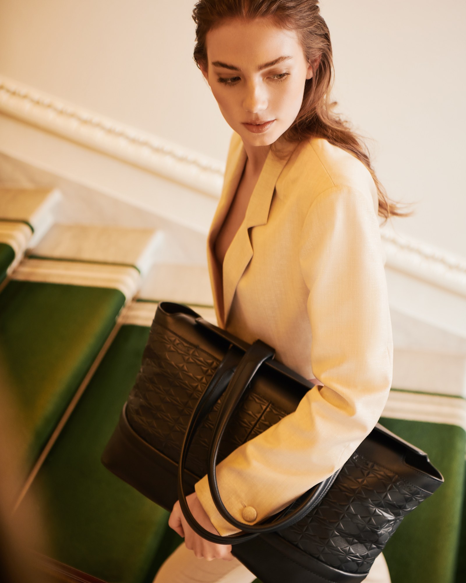 Modella con cappotto giallo e borsa in pelle nera