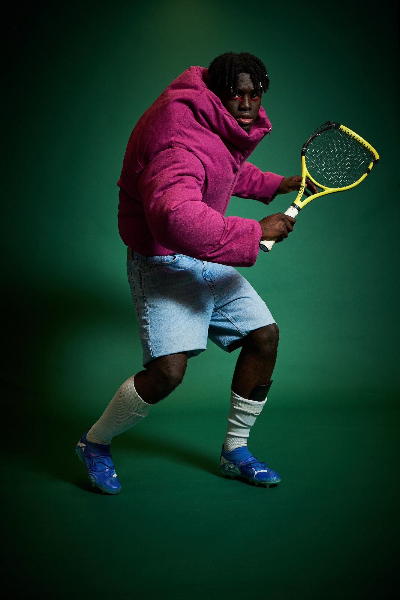 Modello con piumino fucsia e racchetta da tennis su fondo verde