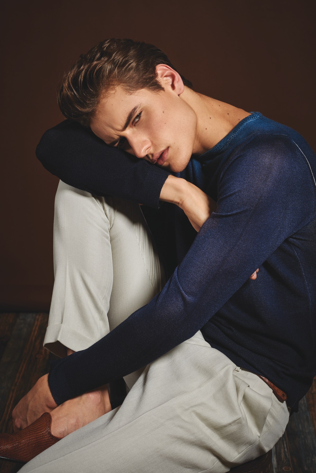 Modello seduto con maglione blu e pantaloni chiari
