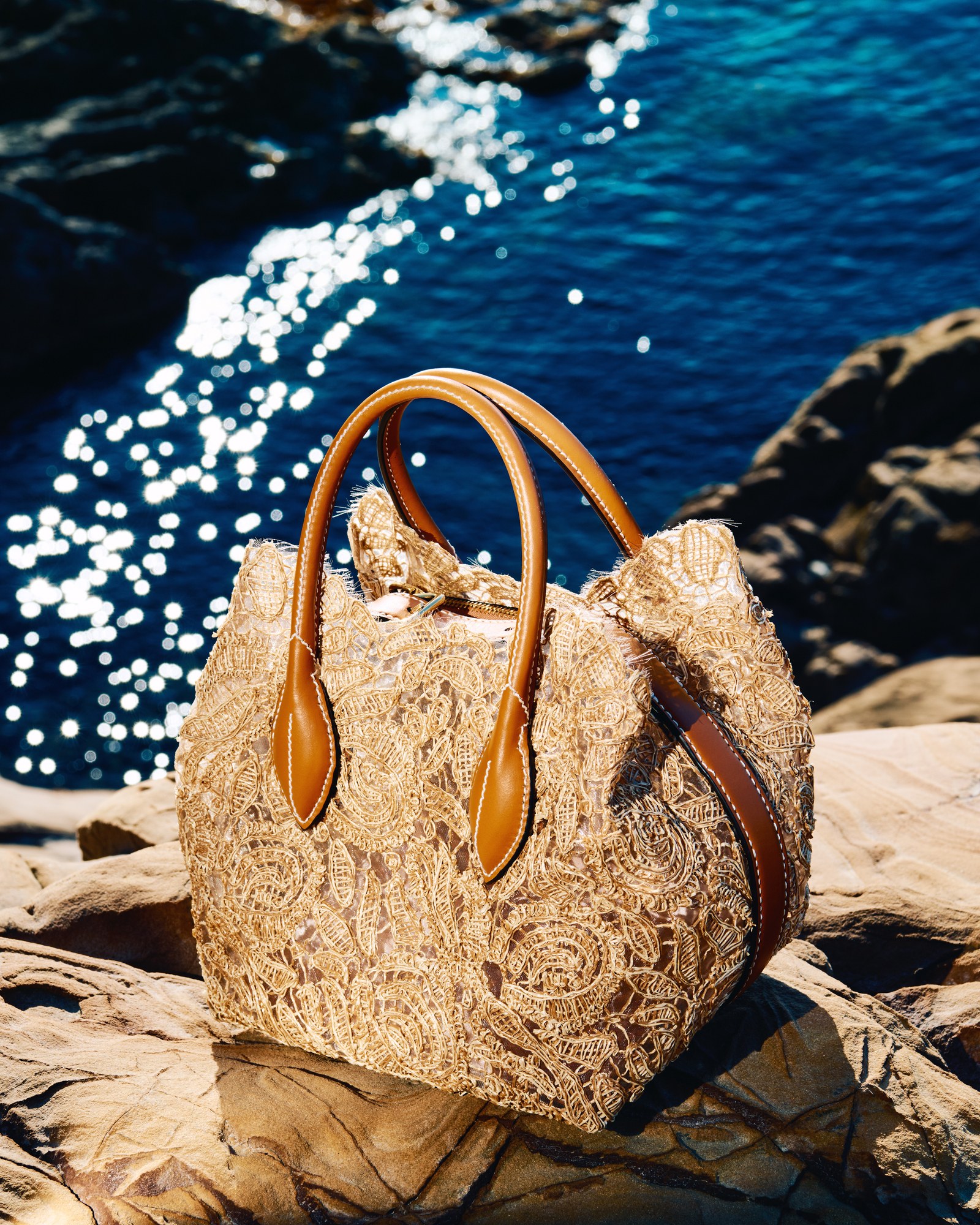 Borsa in pizzo con manici in cuoio sugli scogli sul mare