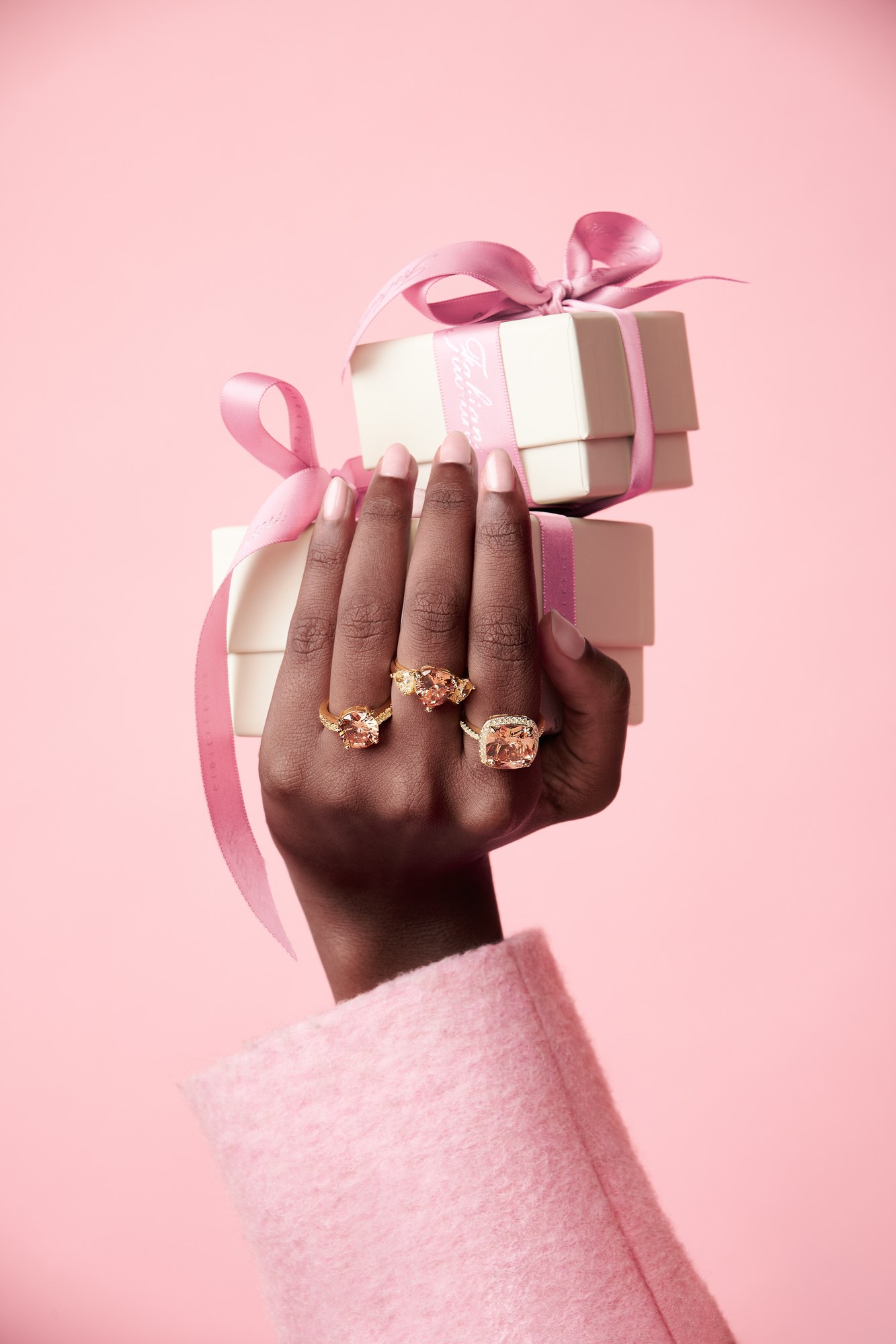 Mano con anelli che regge una scatola regalo rosa