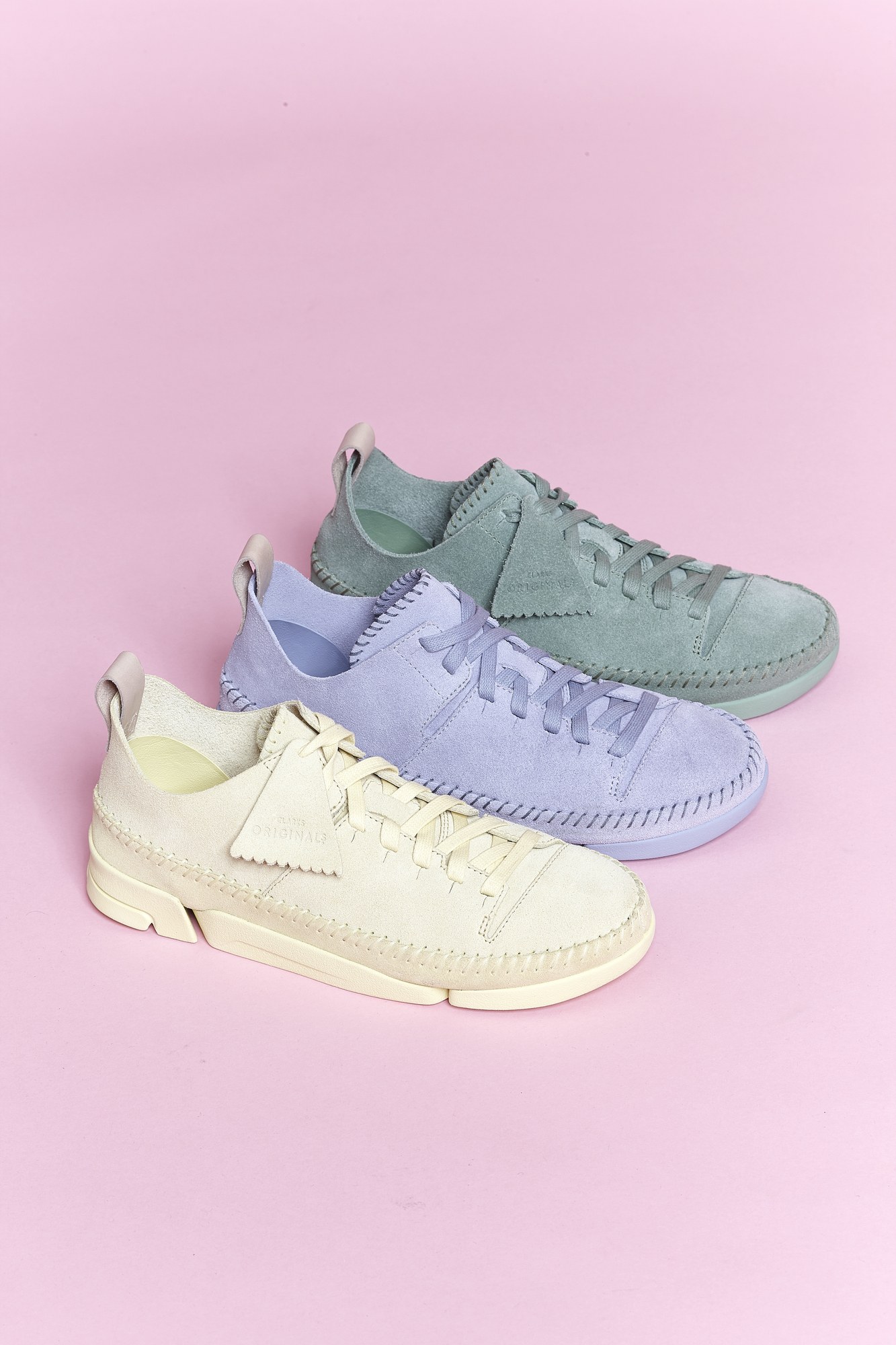 Tre sneakers in camoscio pastello su fondo rosa