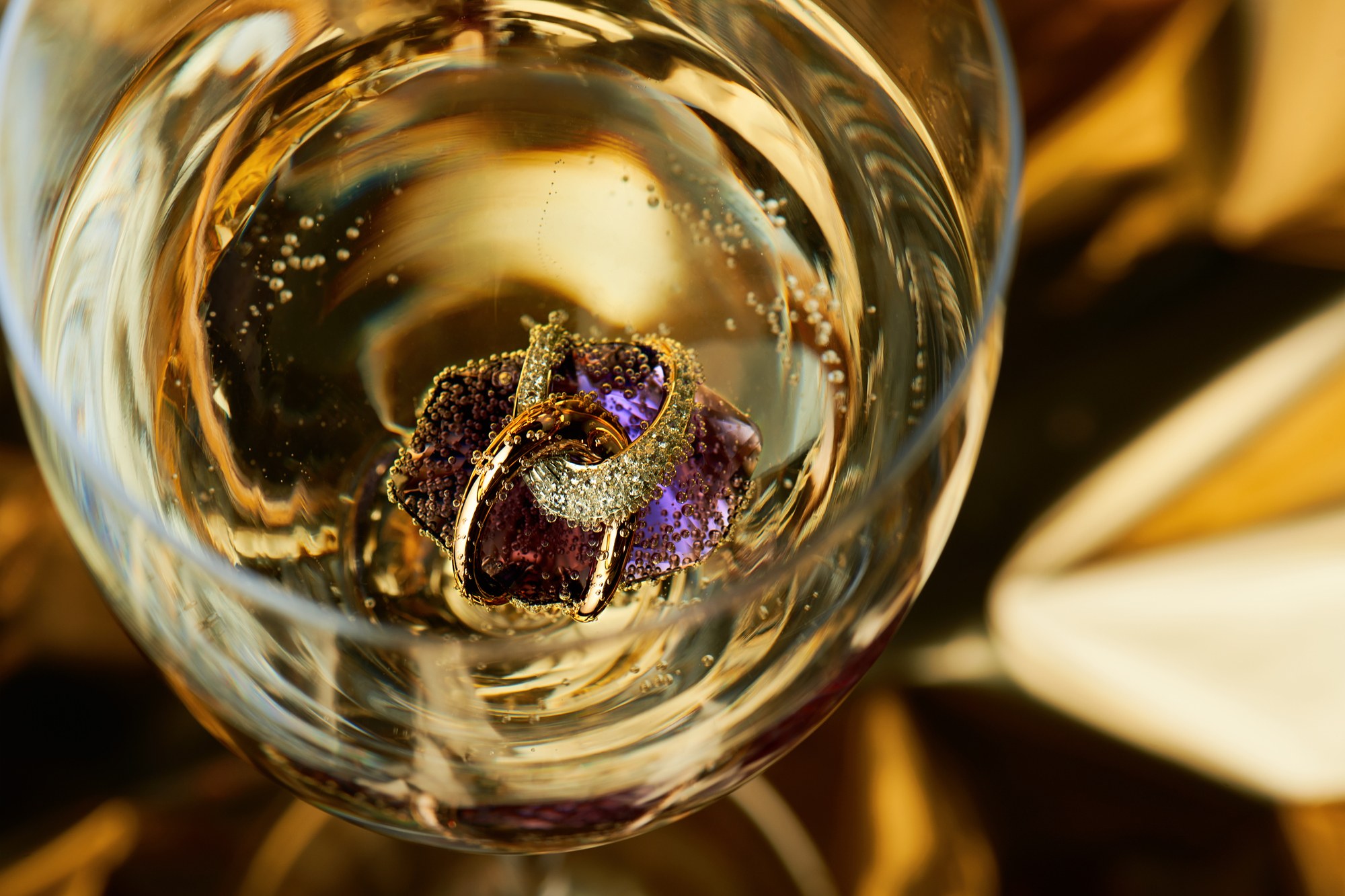 Gioiello con ametista immerso in un bicchiere di vino bianco
