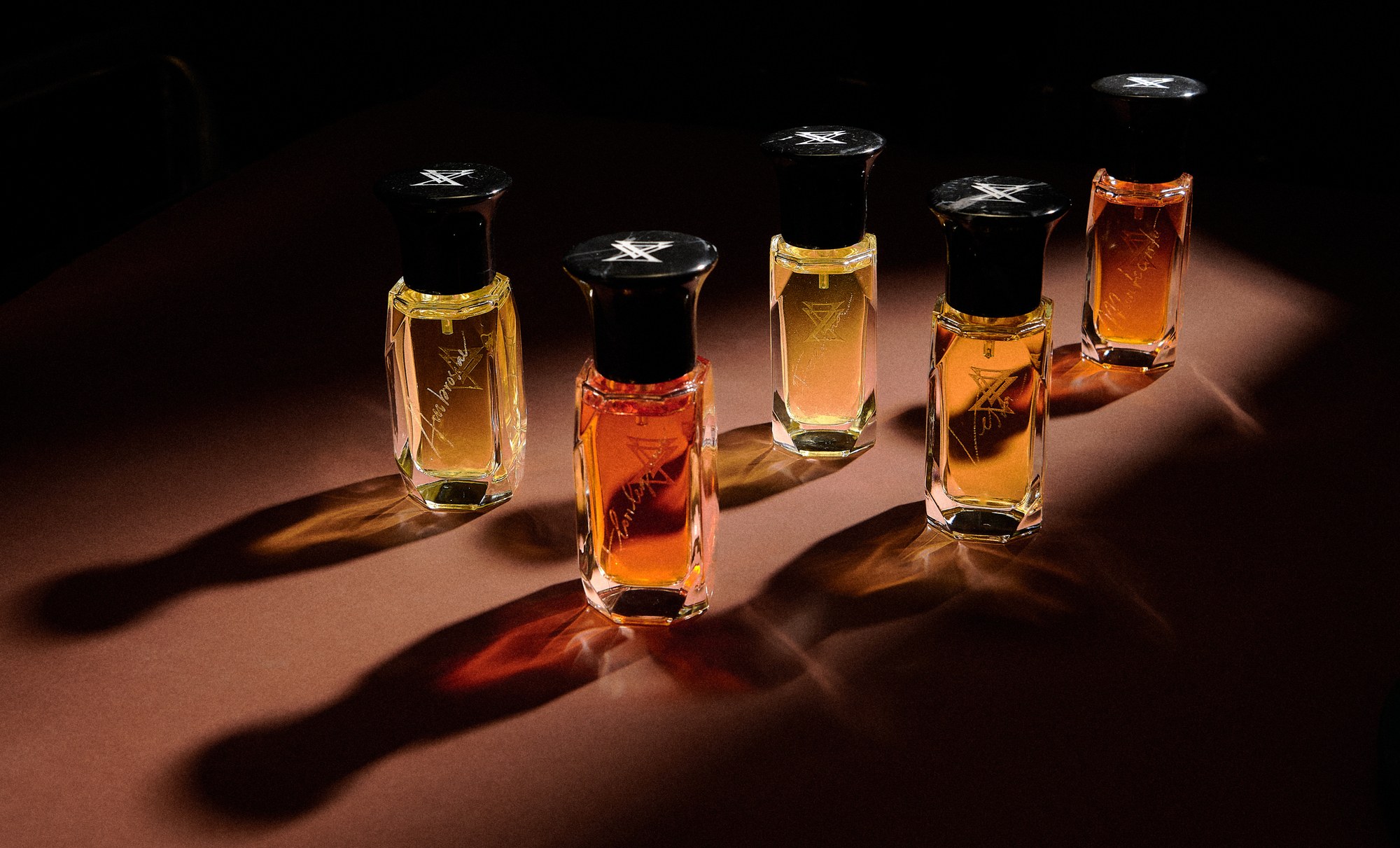 Flaconi di profumo in vetro con ombre lunghe su fondo scuro
