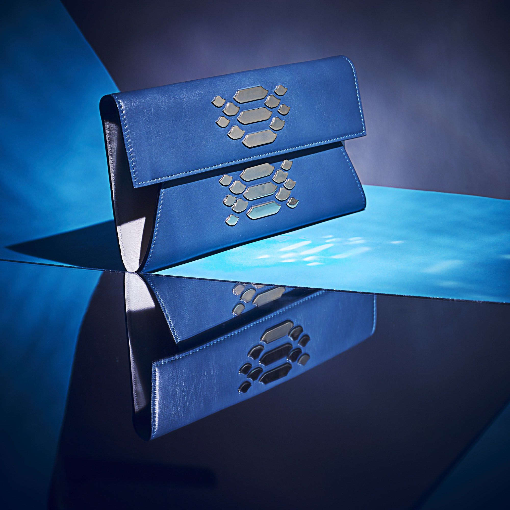 Pochette in pelle blu con riflesso su superficie lucida